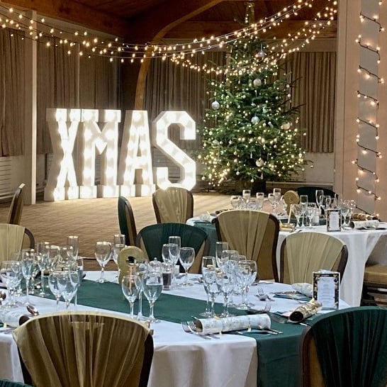Christmas party set up in The Safari Lodge, showing big lit up sign saying XMAS, Christmas tree and tables