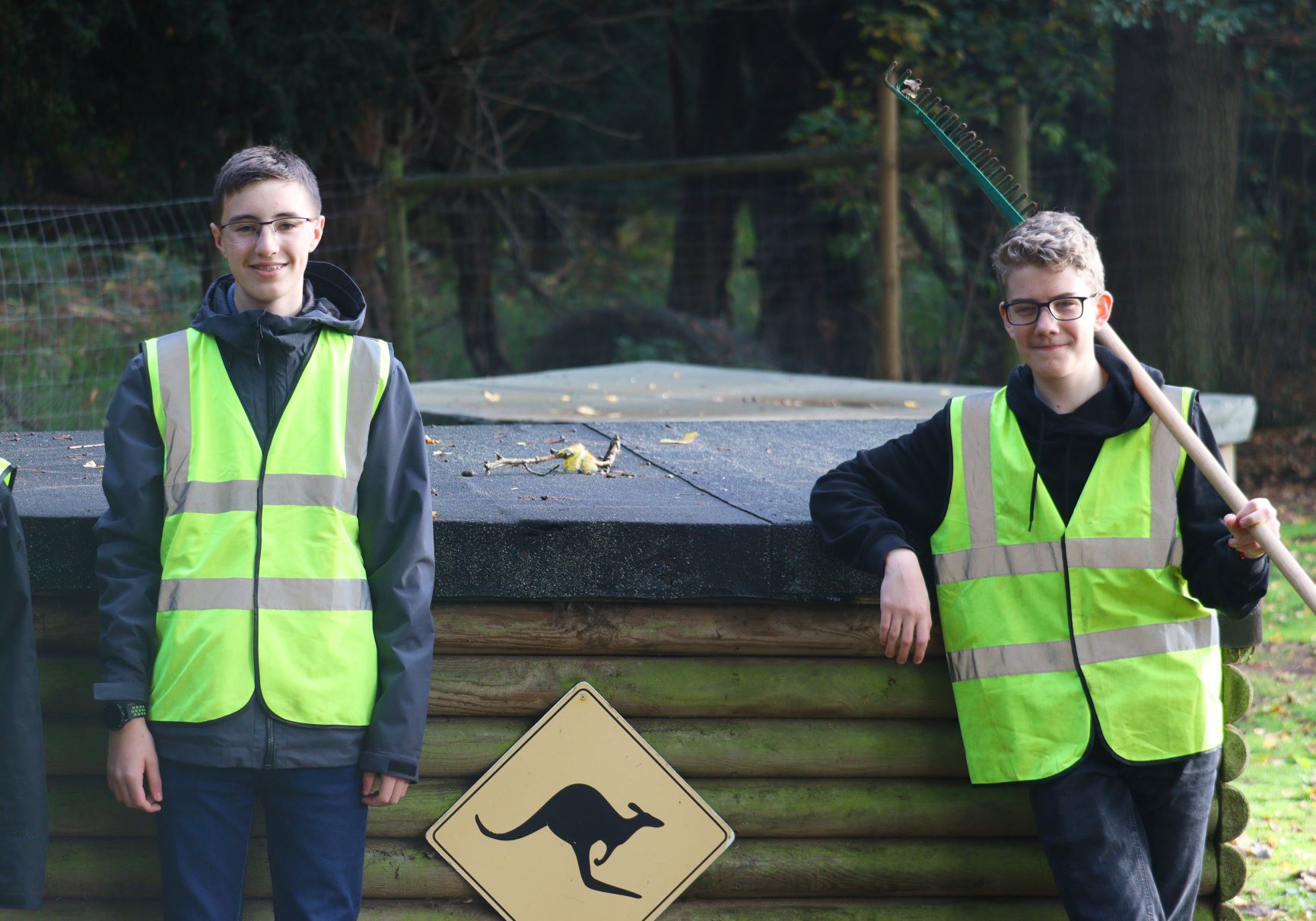 Boys pose in front of wallaby sign with cleaning tools 