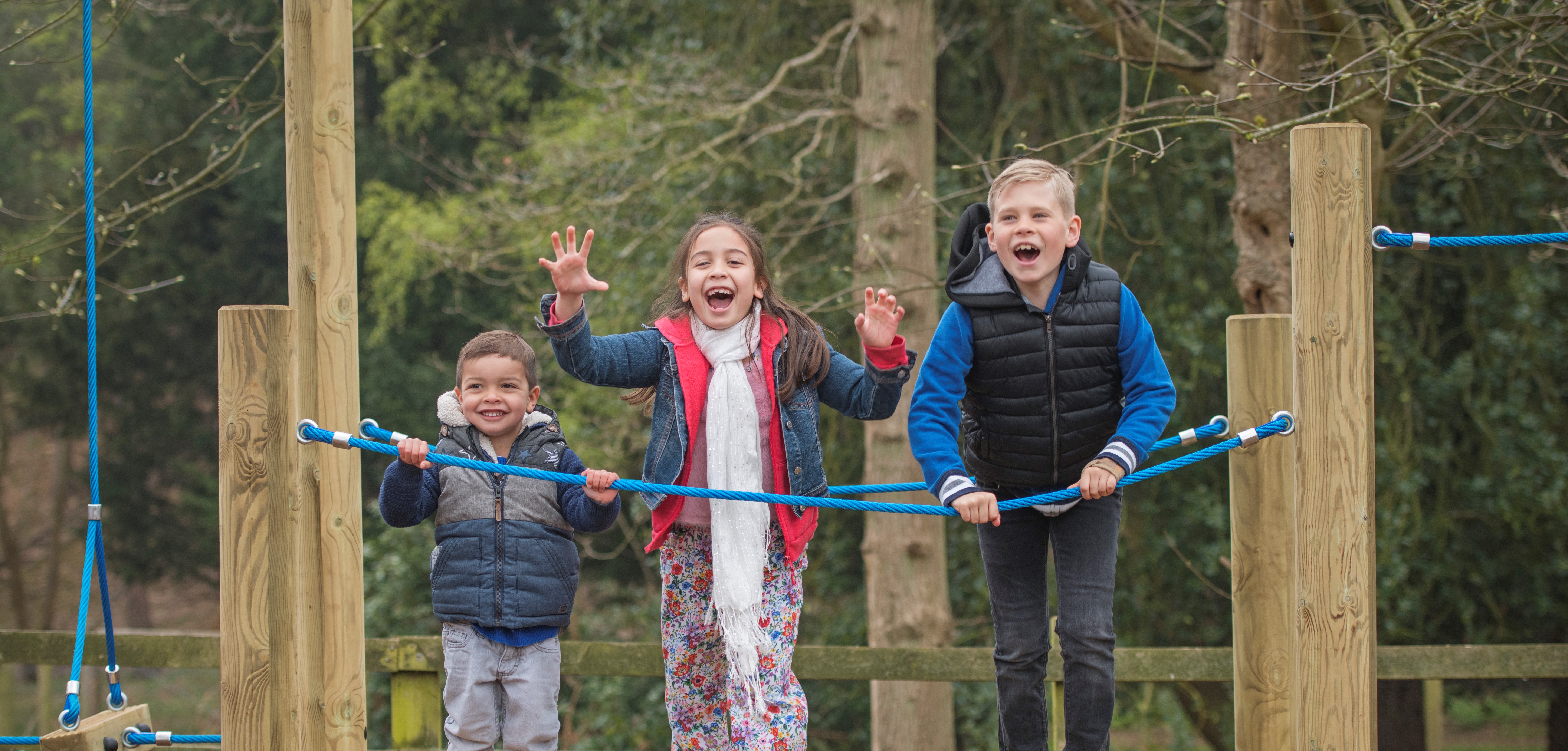 Three children play on outdoor play equiptment